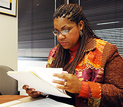 Woman reading through papers at desk.